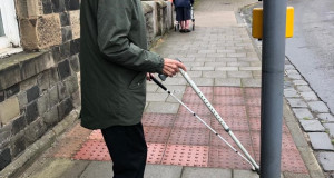 Veteran David Murray stands with his long cane at a road crossing
